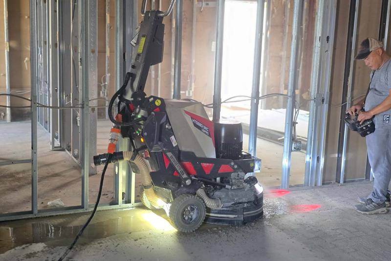 Grinder removing old flooring adhesive near a window